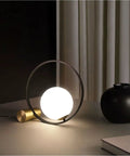 Mid Century Modern Nightstand Lamp in Black Matte Metal with Frosted Glass Globe illuminating a desk in a living room setup