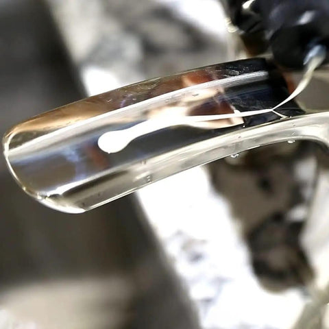 Close-up of Faucet Wax Plus 7.6oz USA Made Water Based Cleaner applied to a chrome faucet for removing stains and fingerprints.