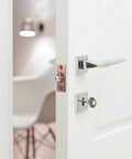 Adjustable pink brass door catch with roller beads on a white door, showcasing heavy duty lock for cupboards.