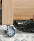 Close-up of 5 Inch Locking Swivel Casters With Brake, 1/2-13 X 1.5 Threaded Stem, Grey TPR Rubber Wheels on furniture leg.