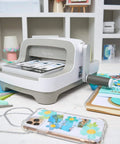 All In One 6 Inch Die Cutting And Embossing Machine Starter Kit for crafters on craft table with accessories and scrapbook