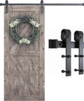 Wooden barn door with mounted wreath and hardware, showcasing 6.8FT Barn Door Hardware Kit with J Shape hanger and sliding track system.