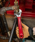 Adjustable Drive Wrench With Extra Capacity Jaw used on a pipe, 12-Inch forged alloy steel with high polish chrome finish, red handle