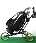 Slick Foldable Three Wheeled Golf Cart Crafted From Solid Aluminum Alloy with golf bag, green wheels on putting green.