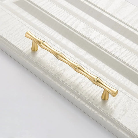Bamboo Shape Solid Zinc Alloy Cabinet Knobs Set Of 6 In Golden Finish for drawers with smooth edges, shown installed on a panel.
