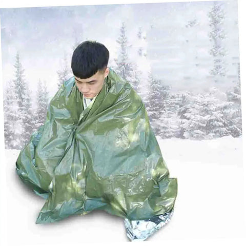Person wrapped in a 3 Pack Rescuing Survival Warm Blankets with First Aid Kit for camping in a snowy landscape