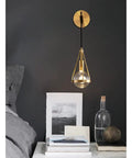 Slick Premium Copper LED Wall Sconce Featuring Glare Free Crystal Shade For Modern Bedroom Bedside Hallway And Staircase Decor showcased above a bedside table.