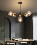 Six Light Glass Globe Sputnik Chandelier In Matte Black With Amber Shade in modern dining room setting.