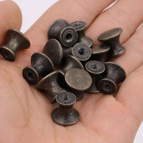 10 Pcs Vintage Bronze Drawer Pull Handles Zinc Alloy Mini Metal Knobs held in a hand, showing compact size and bronze finish.