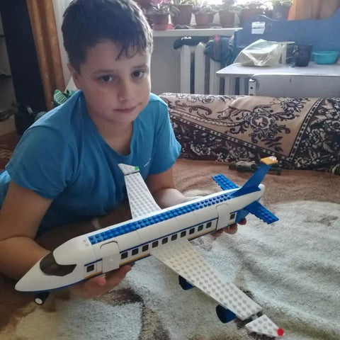 Boy holding airplane from City Airport Building Block Set For Kids Aged 6 To 12 With 463 Pieces Plane Station And Helicopter Build Kit