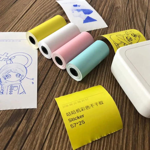 Four rolls of colorful square thermal receipt paper 57x25 mm for Mini POS printers on a wooden table.