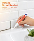 Hand using Grout Fix Pen For Tile Grout Lines Waterproof Tile Repair Marker For Ceramic Walls And Floors Quick DIY Refresh In Kitchen Bathroom With Bright White Finish on white tiles.