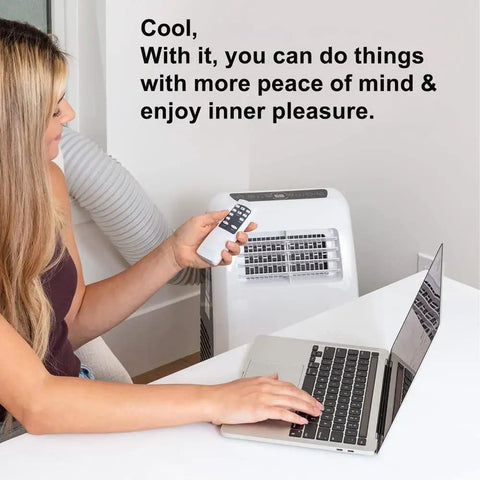 Woman using remote to operate a portable AC unit with exhaust hose coupler window adapter, laptop on desk.