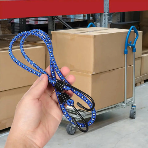 Person holding blue rubber bungee cords with buckle hooks in warehouse, boxes and dolly in background.