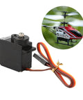 Badass 10g Metal Gear Micro Servo Featuring Solid Core Motor And Lightning Fast Digital Response For 450 Rc Helicopter Builds And Tight Control Upgrades That Go Hard On The Field, black with wires, next to RC helicopter.