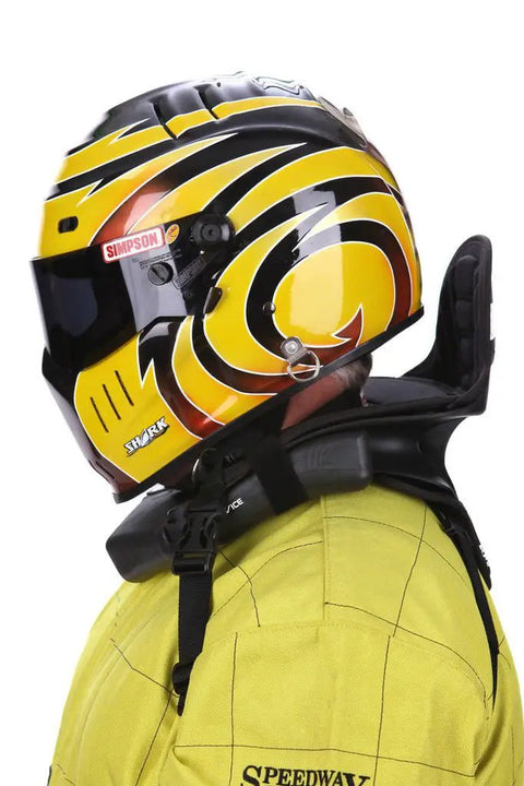 Person wearing 360 Plus Neck Collar for adults in go kart racing with yellow helmet, stabilizes head movement, durable nylon core.