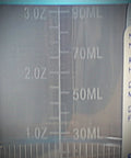 Clear plastic graduated cylinder with 3 oz and 50 ml markings; close-up view.