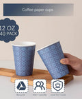 12 Oz Navy Floral Disposable Paper Cups, Image of 240 Pack 12 Oz Disposable Paper Cups Navy Floral Hot And Cold Bev Cups For Home Office Restaurant And Events Leak Proof With Rolled Rim And Poly Lined Interior, hand holding one of the cups