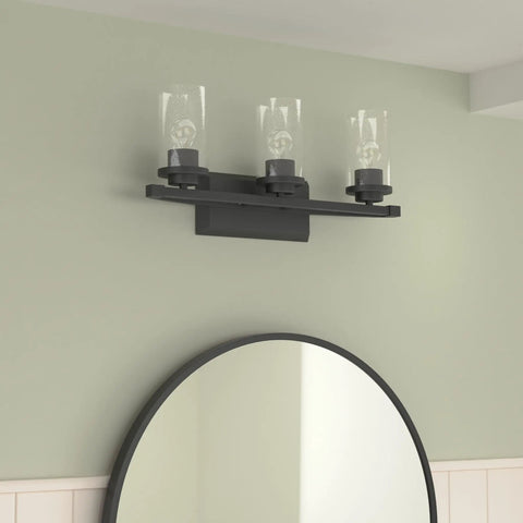 Mercer Matte Black Bath Fixture With Open Cage Design And Seeded Glass on wall above round mirror