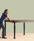 A woman uses No Sweat Heavy Duty Furniture Sliders And Movers For Carpet And Hardwood Floors Reusable Floor Saving Kit to move a table.