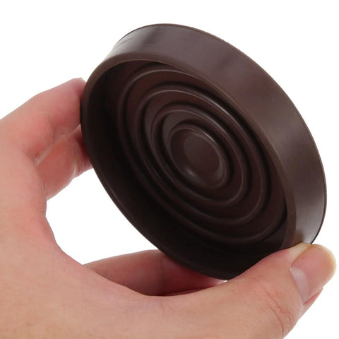 Person holding a brown foot pad from Four Pack Brown Rubber Furniture Foot Pads For Chair And Table Legs Non Slip Round Protectors Easy To Install Reduces Friction On Hardwood Floors Keeps Floors Quiet And Scratch Free.
