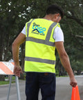 Custom Printed High Visibility Safety Vest In Vivid Yellow With Reflective Striping For Road Crews And Construction Teams Hella Bright Job Site Workwear Size X Large, worn by a man, showing back and logo