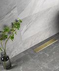 16 Inch Linear Shower Drain With Removable Cover Grid, Brushed Gold Stainless Steel SUS304, shown in bathroom floor