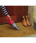 Person using Compact Lithium Hand Vacuum Kit With 2Ah Battery For Cars And Home Multi Surface Cleaning Lightweight Cordless Design on doormat.