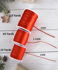 Three spools of red nylon satin cord in sizes 2mm, 1.5mm, and 1mm on a white wooden background with holiday decor