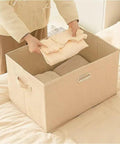 Person placing folded clothes into a Heavy Duty Fabric Storage Bin With Snap On Lids Stackable Khaki Storage Box.