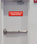 Hella Durable Fire Sprinkler Riser Room Sign Two Pack Self Adhesive Aluminum Warning Tag For Home Garage Or Business Reflective Weatherproof Fade Resistant 9X3 Inch Safety Label on a door.