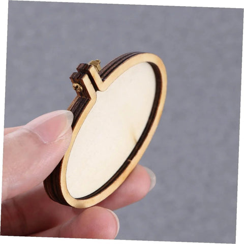 Hand holding a small elliptical wooden hoop from the Five Piece Mini Wood Embroidery Hoops Set With Screws For Cross Stitch And DIY Needlework.