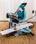 Makita LS1019L 10-inch dual-bevel sliding miter saw with laser, turquoise blade guard on a metal stand.