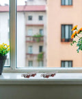 Four Piece Sliding Door Rollers With Double Wheel Bearing Track Pulleys For Smooth As Butter Glide on windowsill with flowers.