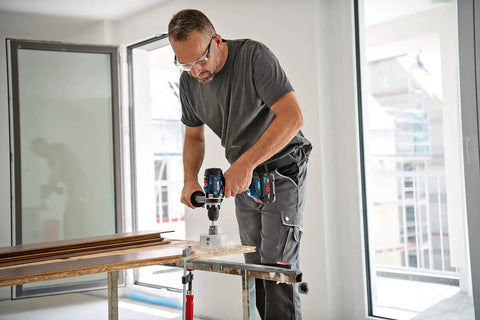 Man using 18V Cordless Combi Drill with 150 Nm Torque Brushless Motor Pro Grade Power Tool on wood surface.