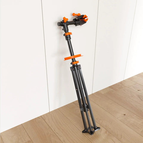 Foldable Bike Repair Stand with Magnetic Tool Tray and 360 Degree Head, folded against a wall, lightweight 6.6kg, max load 66lbs
