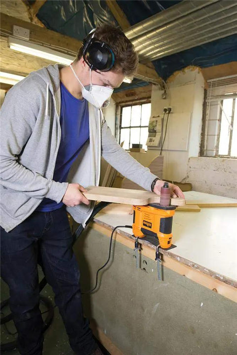 Young man using Heavy Duty 650W Portable Oscillating Spindle Sander With Variable 1800 To 3200 RPM Speed for edge sanding.