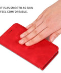 Hand touching a red leather wallet case with smooth texture.