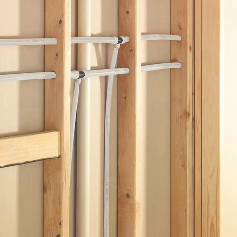 3/4 Inch White PEX Water Tubing Coil, 100 Ft, installed between wooden wall studs, showing flexibility and freeze resistance.