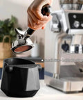 Hand using espresso machine over diamond shape mini espresso knock box for home use quick coffee grounds cleanup with included cleaning brush barista essential