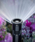 Adjustable Spray Nozzle With 0 To 360 Degree Arc And 15 Ft Radius Delivers Precise Pop Up Sprinkler Performance For Lawn And Landscape Irrigation With Even Coverage And Water Savings No Fuss Setup spraying water over plants