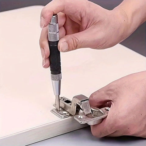 Heavy Duty Badass Automatic Center Punch Tool used on metal hinge for precise marking on wooden surface.