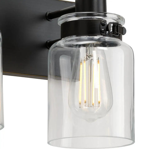 Close-up of Vintage Farmhouse Bath Vanity Light With Clear Glass Shades, 4 Light Antique Bronze Finish, Warm Mid Century Modern Vibe For Bathroom Remodel, Industrial Style Fixture For Elegant Surroundings.