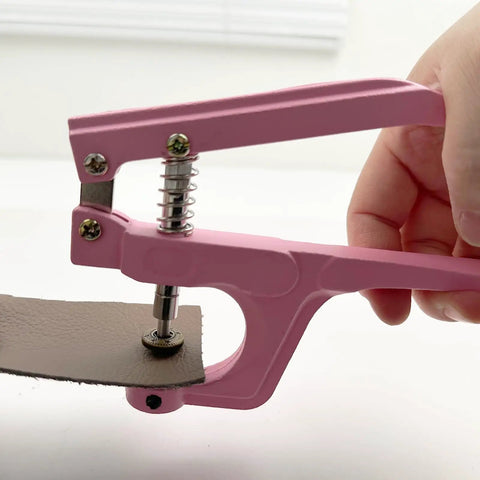 Close-up of pink pliers installing a metal snap on leather, part of 50 Sets Metal Snap Buttons Kit With Pliers 15mm Leather Snap Fasteners.