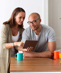 Couple using tablet with T5 Plus WiFi Touchscreen Smart Thermostat With 7 Day Flexible Programming Geofencing Technology Black on wall.