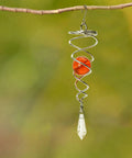 Stainless Steel Wind Spinner Tail Gazing Ball Stabilizers For Indoor And Outdoor Decor With Hanging Swivel Hook Glass Ball Accent Weatherproof Garden Ornament Kit To Elevate Patio And Yard Vibes. Hanging stainless steel wind spinner with orange glass ball and clear pendant on branch