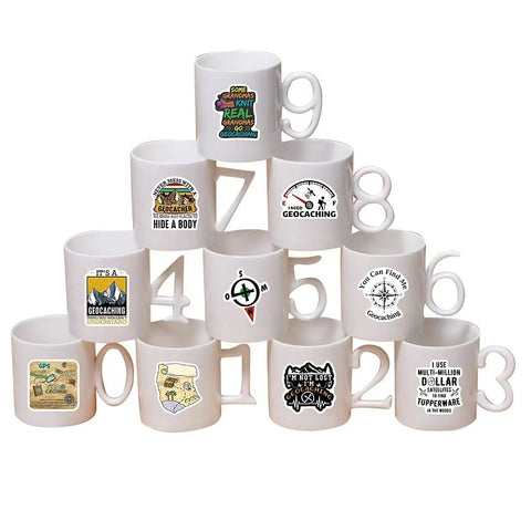 White mugs with geocaching vinyl decals in a pyramid, showcasing designs part of 50 Piece Waterproof Geocaching Stickers Pack Vinyl Decals For Water Bottles Laptops Luggage Bicycles Skateboards Computers And More Rad Adventure Gear Decor.