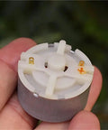 Tiny Powerhouse Mini DC Motor For DIY Projects 32mm Round Spindle With Carbon Brush in hand, showing bottom view