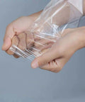 5x7 Inch Shrink Wrap Bags 200 Pcs Pack For Crafting Gift Wrapping And Food Prep Clear Bags You Can Cut To Fit And Seal With A Heat Gun High Shrinkage For Scratch Protection And Tight Compact Packs, clear PVC bag on hands