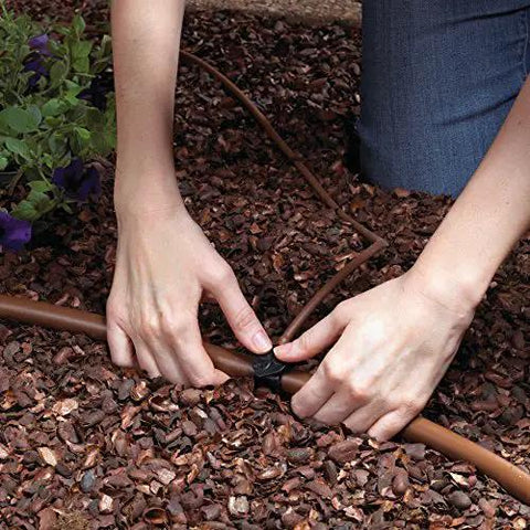 Hands installing Automatic Drip Irrigation Kit With Timer For Ground Cover And Flower Beds, 13 GPH sprayers, brown finish tubing